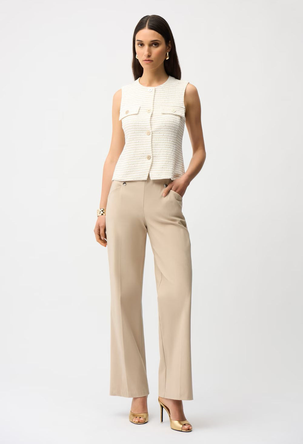 Woman wearing a white sleeveless top and beige pants on a white background