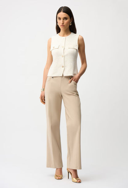 Woman wearing a white sleeveless top and beige pants on a white background