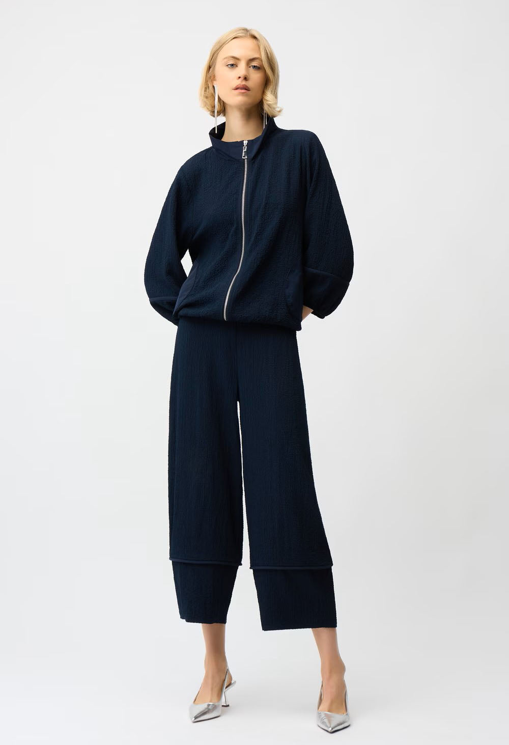 Woman wearing a navy blue outfit with wide-leg pants on a white background