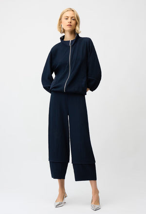 Woman wearing a navy blue outfit with wide-leg pants on a white background