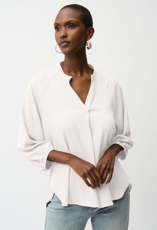 Woman wearing a beige blouse and light blue jeans against a white background