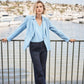 woman wearing a blue blazer and matching blue top standing on the water front