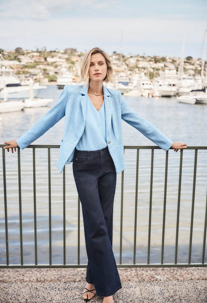 woman wearing a blue blazer and matching blue top standing on the water front