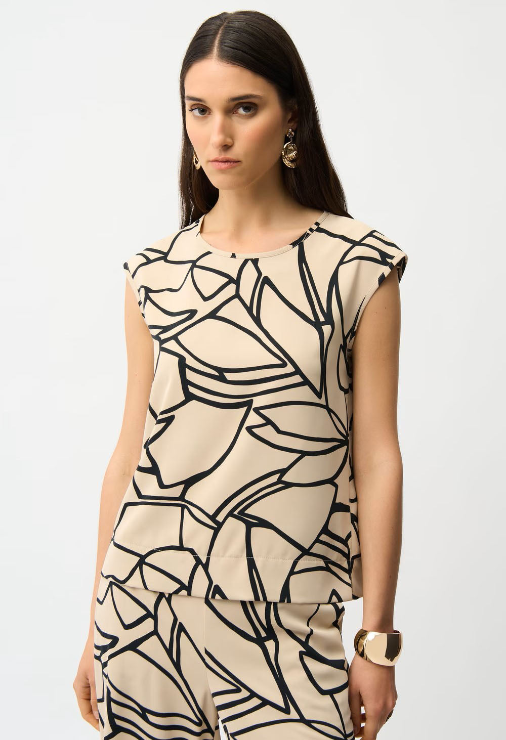 Woman wearing a beige top with black abstract pattern on a white background