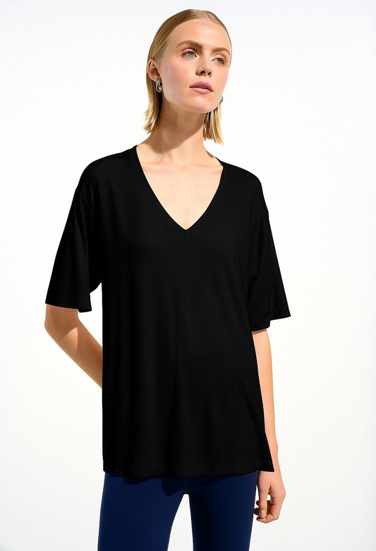 Woman wearing a black V-neck top and blue pants on a white background