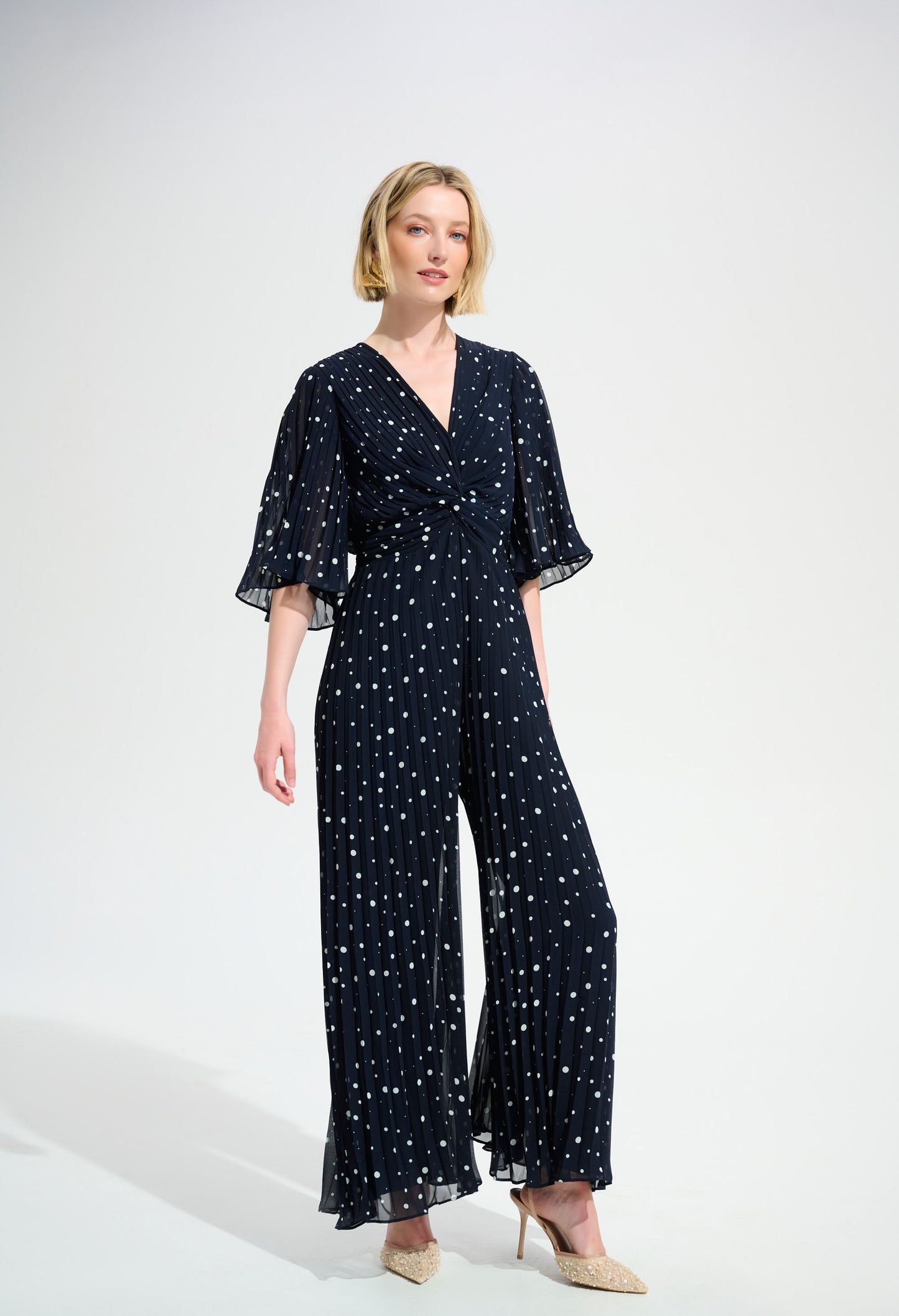 Woman wearing a navy blue jumpsuit with white patterns on a white background