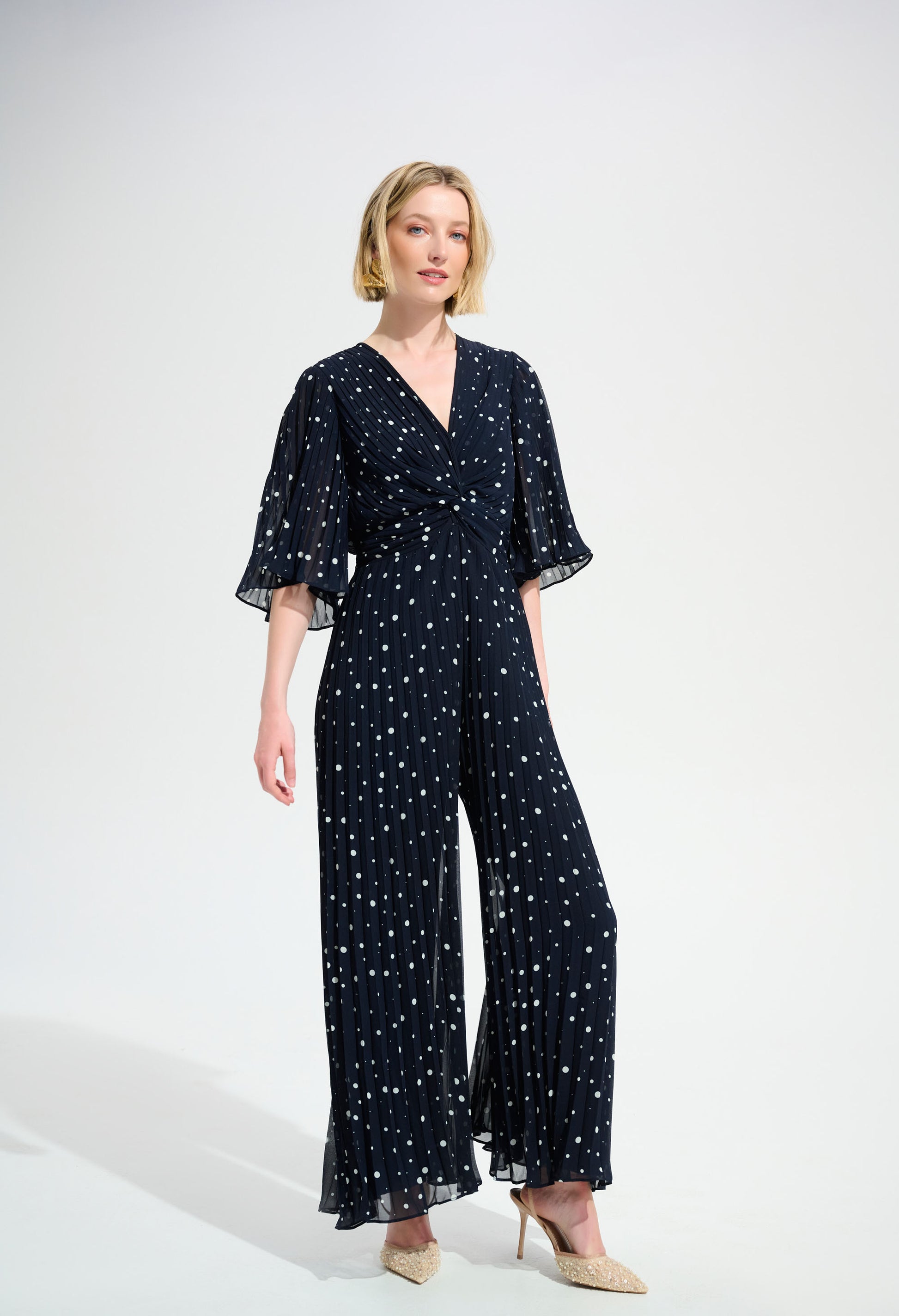 Woman wearing a navy blue jumpsuit with white patterns on a white background