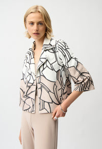 Woman wearing a stylish black and white patterned blouse against a plain background