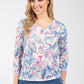 Woman wearing a colorful floral long-sleeve top against a white background