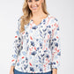 Woman wearing a floral blouse with long sleeves on a white background