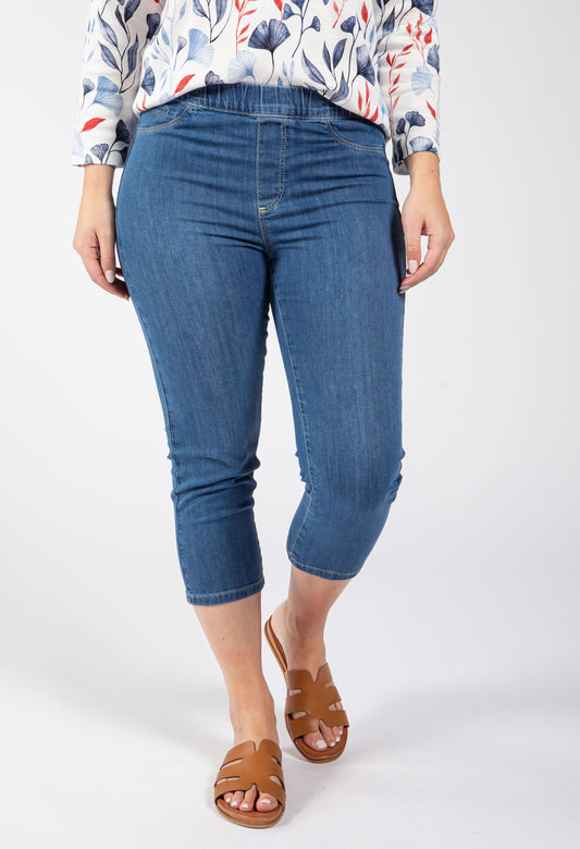 Person wearing blue jeans and a patterned top on a white background