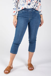 Person wearing blue jeans and a patterned top on a white background
