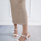 White sandals worn with beige pants on a light gray floor.