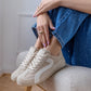 Person wearing white sneakers and blue jeans sitting on a stool indoors.