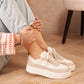 Person wearing white sneakers sitting on a wooden floor with a neutral background