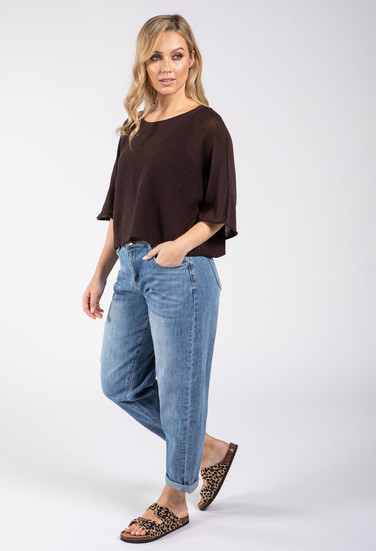 Woman wearing a brown top and blue jeans on a white background
