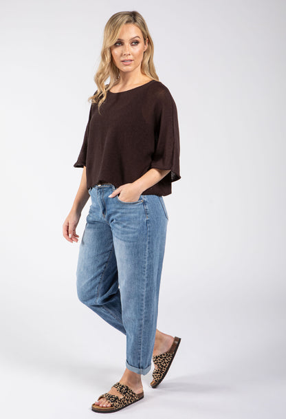 Woman wearing a brown top and blue jeans on a white background