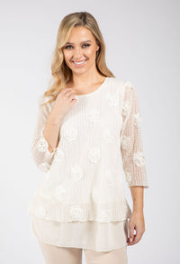 Woman wearing a white lace top against a plain background
