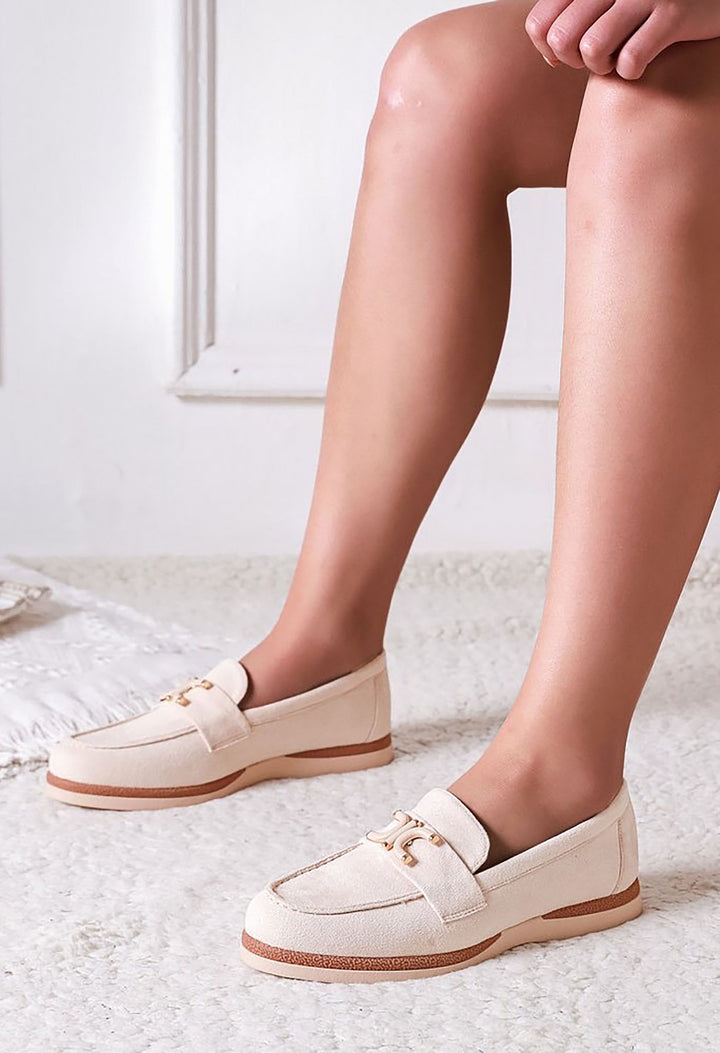 White loafers worn by a person on a light background