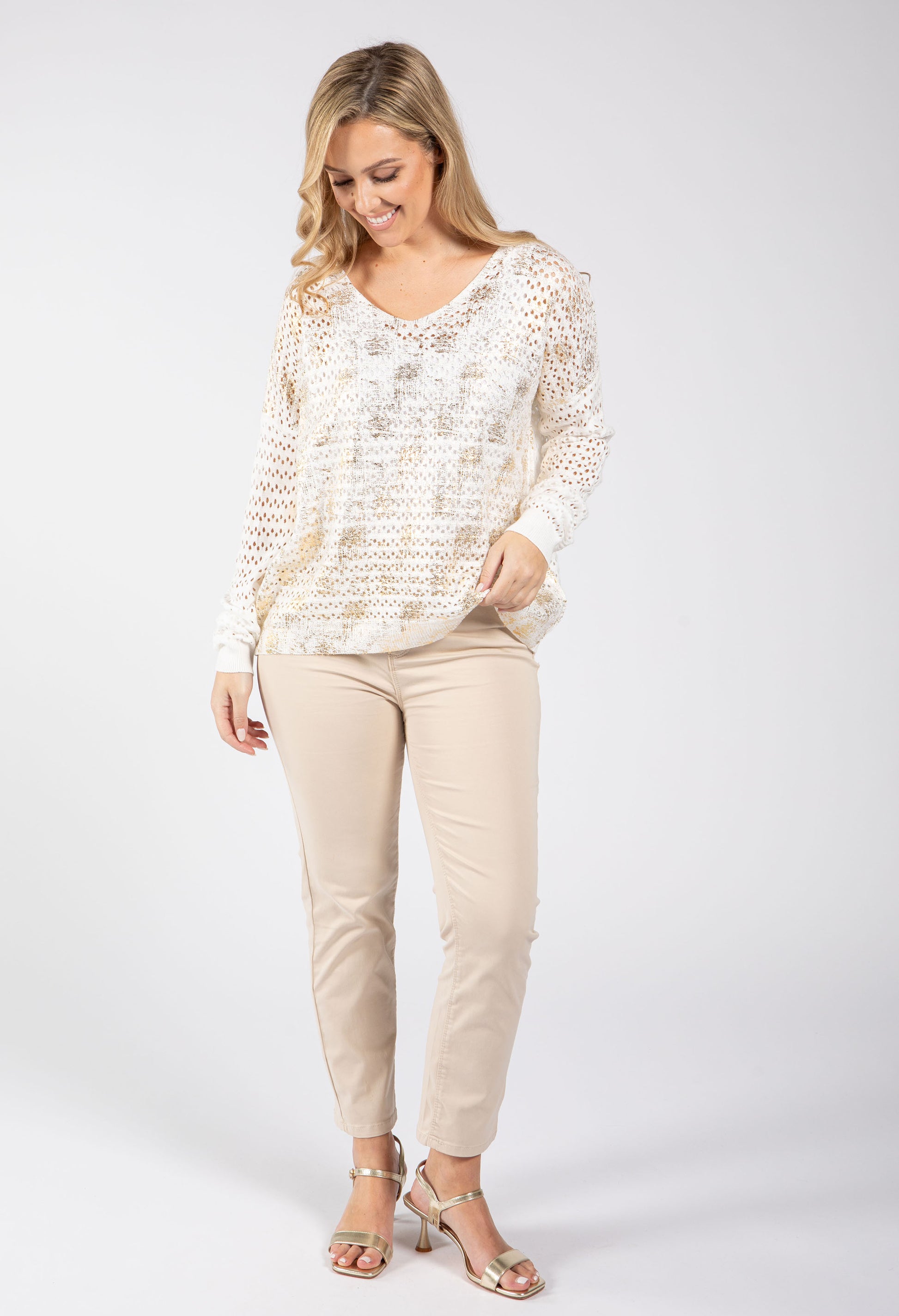 Woman wearing a patterned top and beige pants on a white background