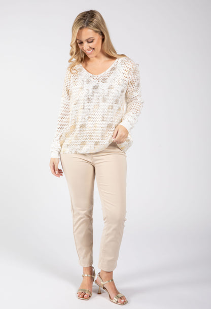 Woman wearing a patterned top and beige pants on a white background