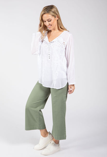 Woman wearing a white blouse and green pants on a white background