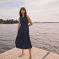 Woman in a navy dress standing on a dock by a body of water.