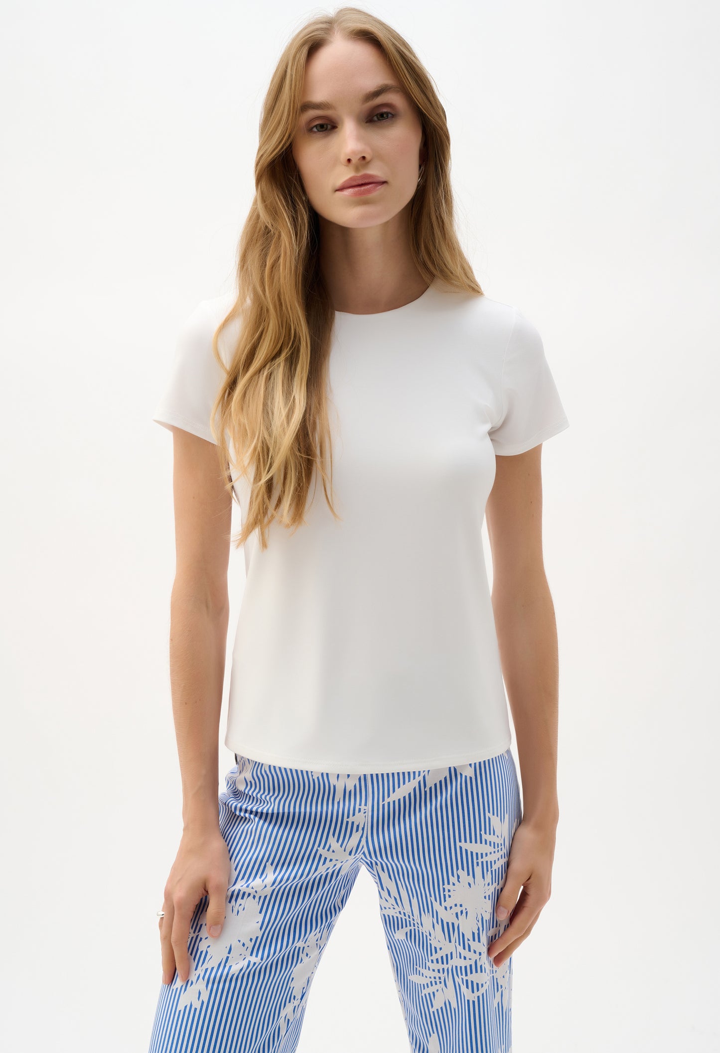 Woman wearing a white top and blue floral pants on a white background