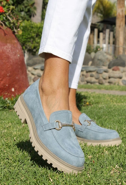 Blue suede loafers worn outdoors on a grassy area