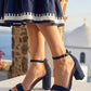 Navy sandals worn with a patterned dress against a scenic background
