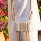 Person wearing a colorful striped handbag with a blurred floral background