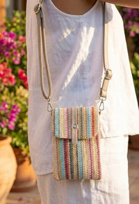 Person wearing a colorful striped handbag with a blurred floral background