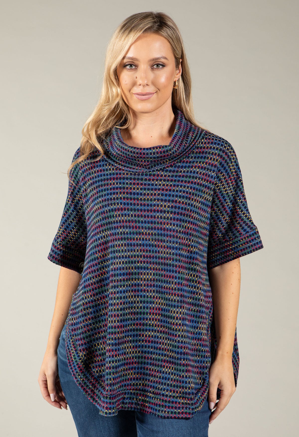 A woman modeling a short-sleeve cowl-neck knit top with a multicolor textured pattern of blue, red, and purple on a solid light gray background.