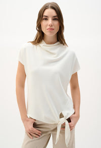 Woman wearing a white cowl-neck top with a tie detail on a white background