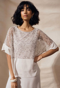 Woman wearing a sparkling top against a beige background