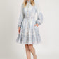 Woman wearing a light blue floral dress with a belt on a white background