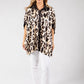 Woman wearing a leopard print shirt and white pants on a gray background