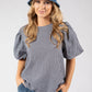 Woman wearing a checkered top, denim shorts, and a denim bucket hat on a white background