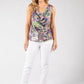 Woman wearing a colorful sleeveless top and white pants on a gray background