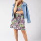 Woman wearing a floral dress with a denim jacket on a white background