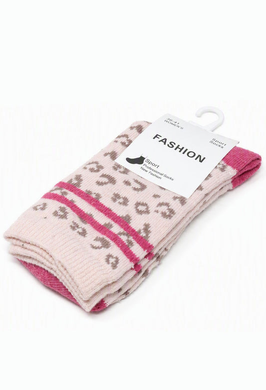 A pair of folded knit socks on a white hanger, featuring a light pink base with a brown leopard print pattern and bright pink horizontal stripes, with a white paper label that reads 'FASHION'.