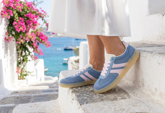 Person wearing blue and pink sneakers on a stone ledge with a scenic background.